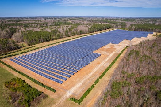 Home Aerial drone shot of a large solar panel farm in a rural area surrounded by forests in North Carolina.