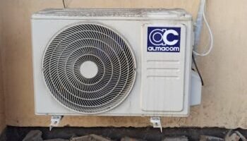 Home A well-used outdoor air conditioning unit affixed to a brick wall, showcasing urban climate control.