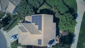 Home Top-down aerial view of a house with solar panels, showcasing modern renewable energy solutions.